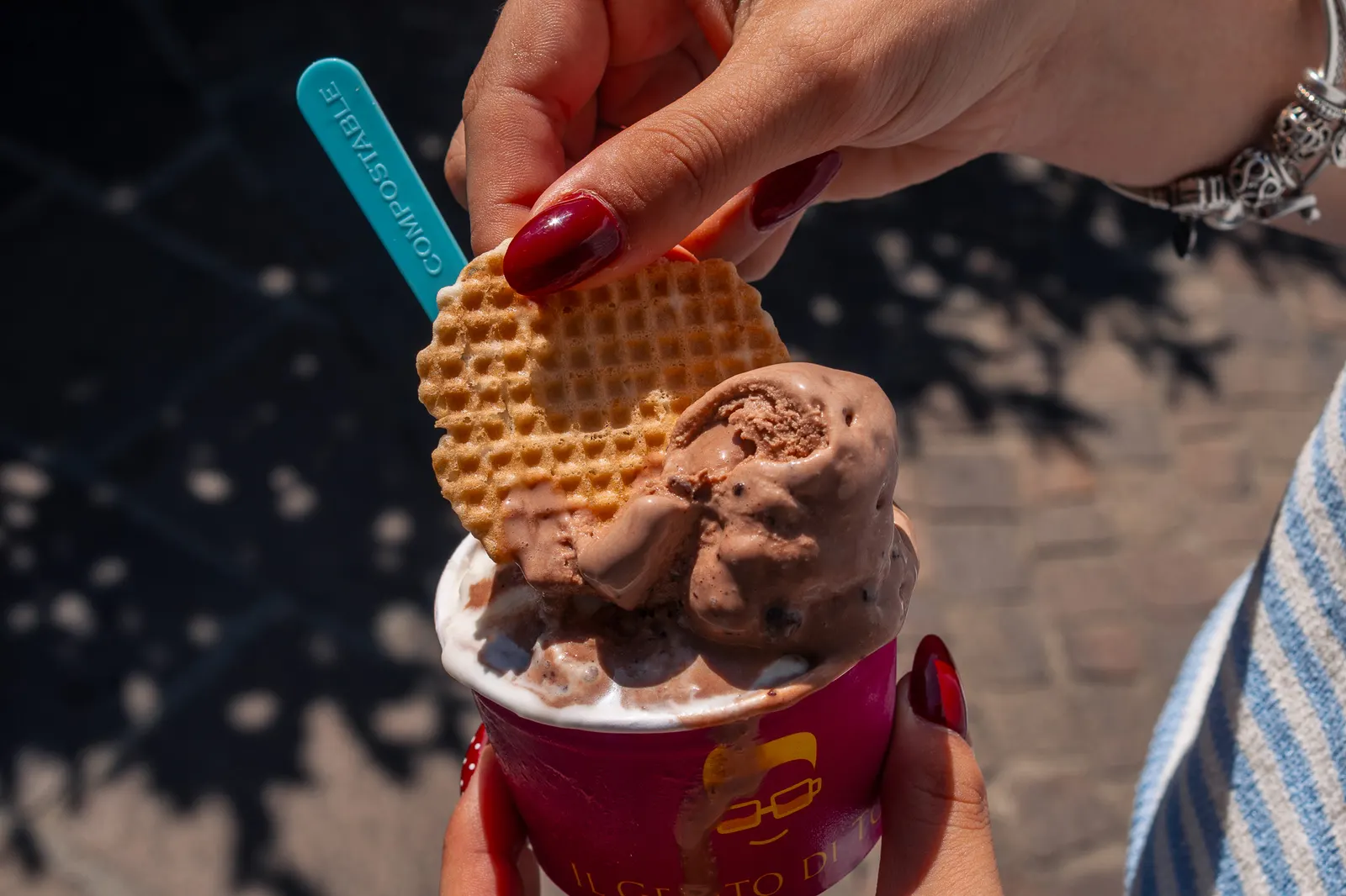 Due mani con una coppetta di gelato al cioccolato e la cialda