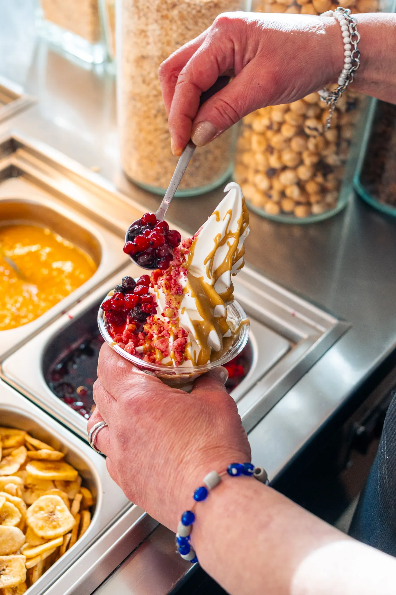 Un cucchiaio solleva frutti di bosco interi sopra una coppetta di yogurt