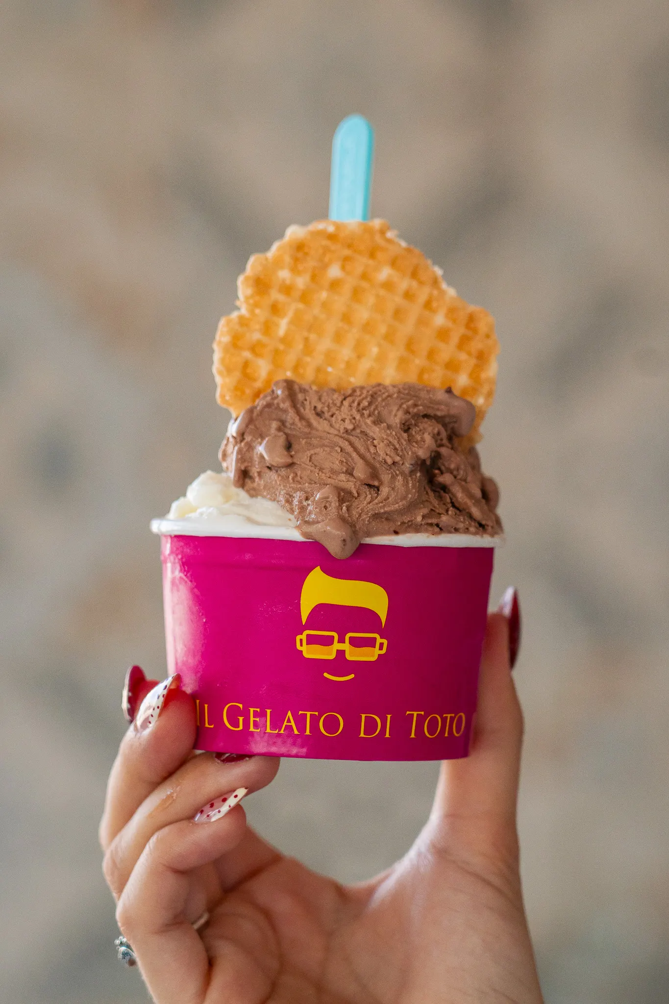 Coppetta fucsia con il logo giallo di Toto, gelato e cialda