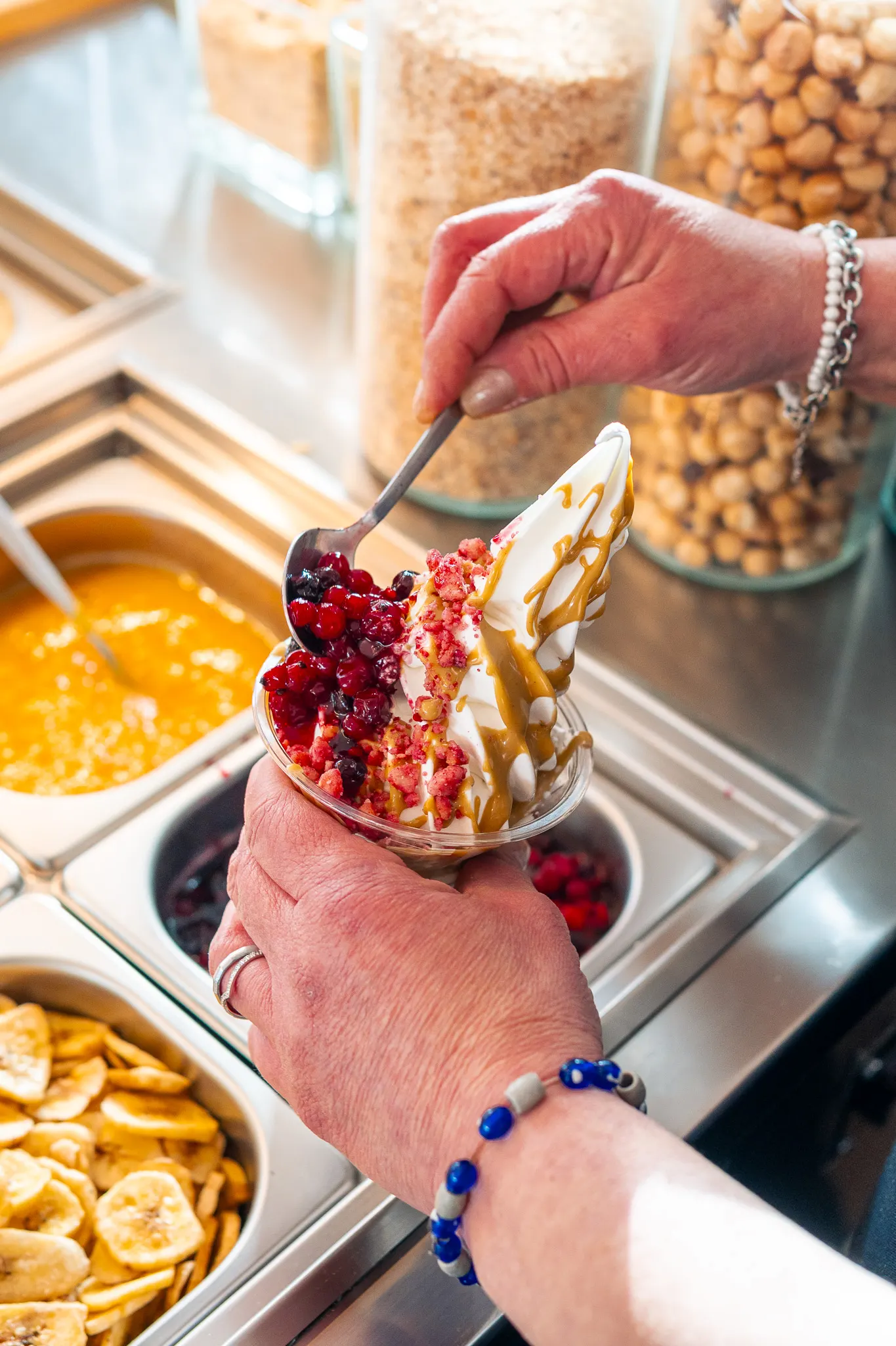 Una mano regge la coppa di yogurt con frutti di bosco e caramello
