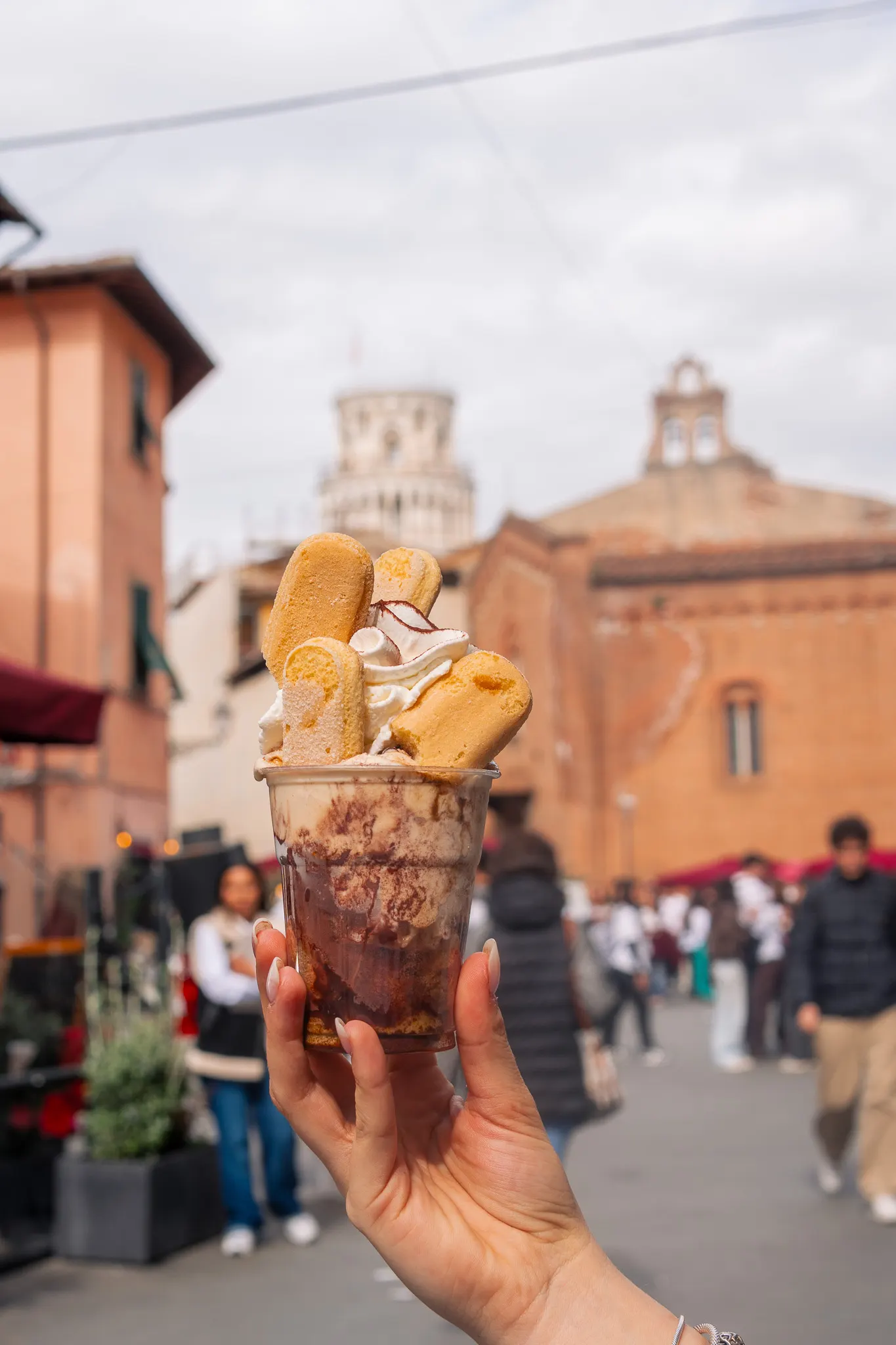 Coppa con gelato e cialde tenuta in mano in centro a Pisa