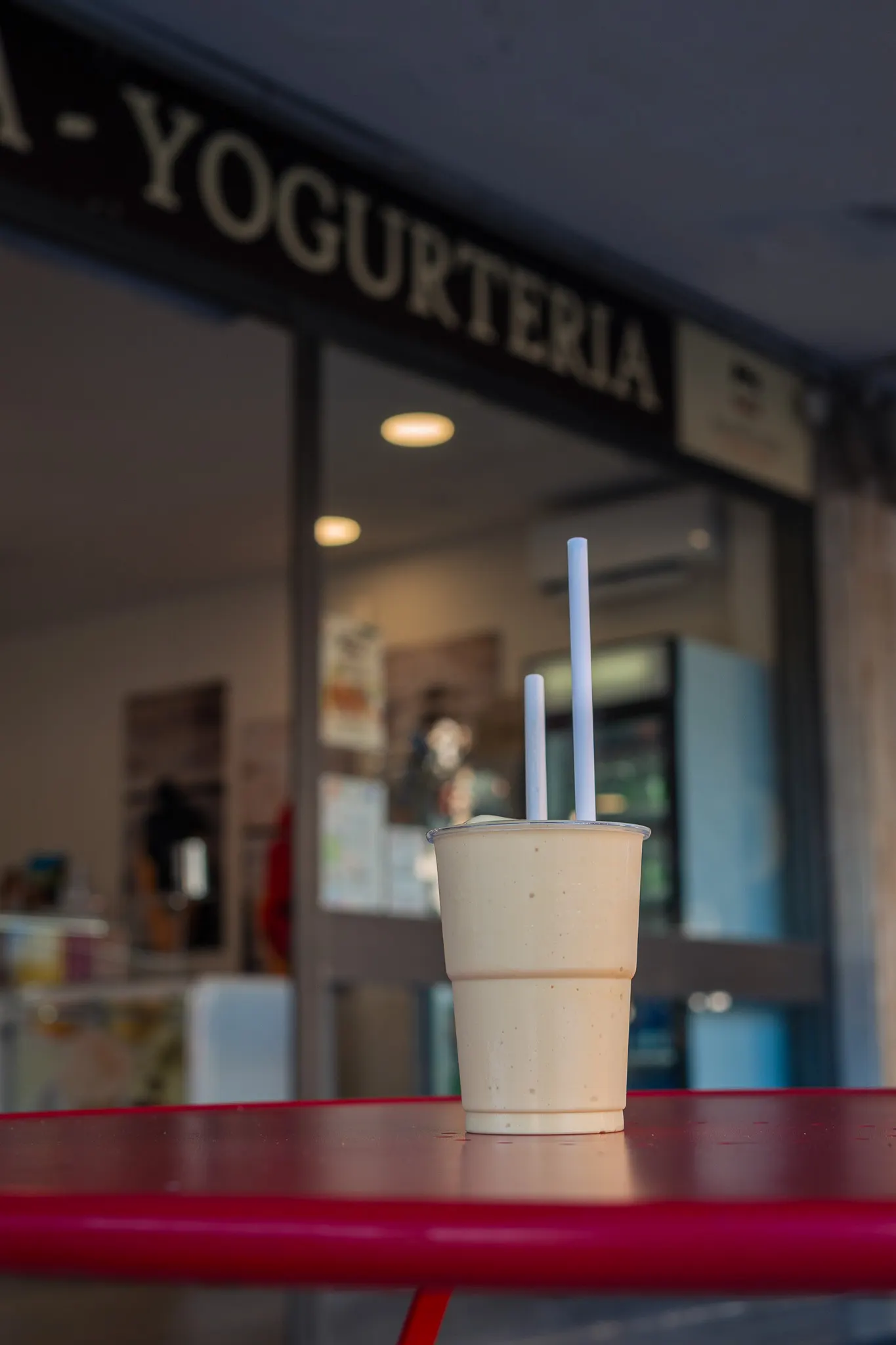 Frullato con due cannucce su un tavolino rosso davanti alla gelateria di Tirrenia